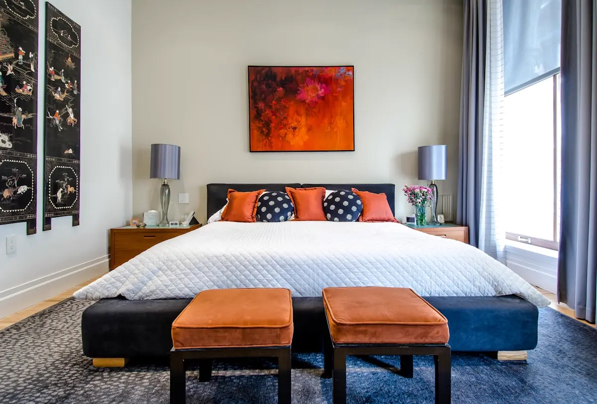 Warmly styled bedroom with twin lamps, soft cushions and a quilted bedspread